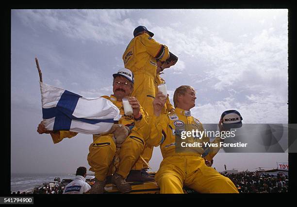 Hari Vatanen and his team celebrate their victory in the car category of the 1990 Paris Dakar Rally by waving a Finnish flag.