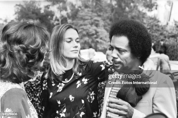 Actress Peggy Lipton puts her arm around the shoulders of music producer Quincy Jones as he talks to another woman at Dean Martin's home in Bel Air,...