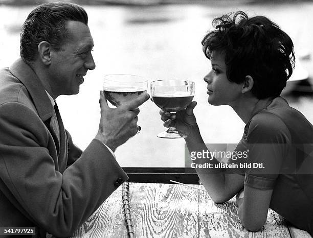 Horst Tappert*-+Schauspieler, Dmit Uschi Glas an einem Tisch; beidehaben ihr Gläser zum Anstossen erhoben- 1970