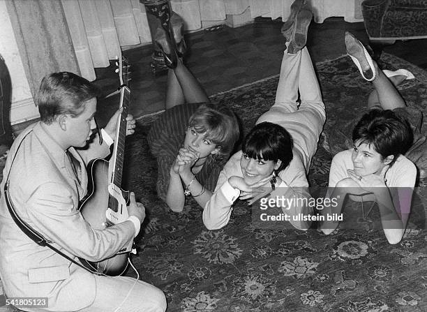 Rene Kollo *-Musiker, Sänger, Tenor, D- spielt E-Gitarre in einer Wohnung;vor ihm auf dem Teppich liegenbewundernd drei junge Frauen- 1961anhänger...