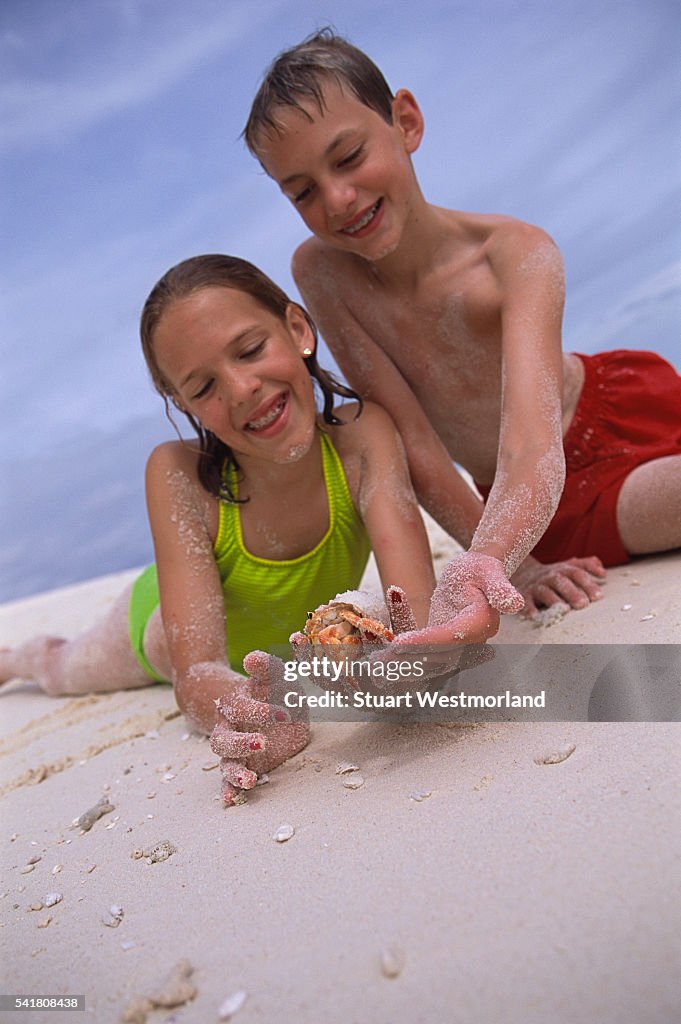 Children on Beach Holding Hermit Crab