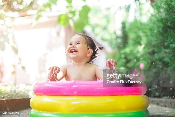 one year old baby playing in baby pool - bad body language stockfoto's en -beelden