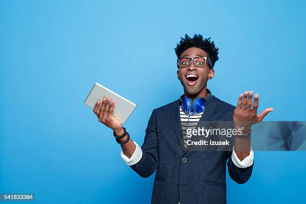 excited afro american guy in fashionable outfit, holding digital tablet - good news stock pictures, royalty-free photos & images