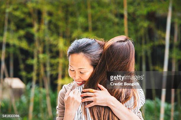 mature japanese woman hugs daughter outdoors in kyoto japan - homecoming stock pictures, royalty-free photos & images