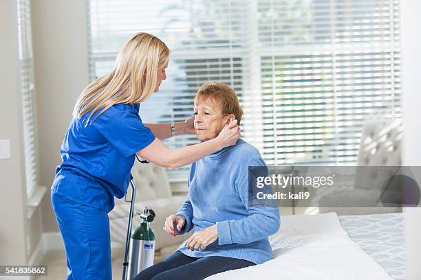home healthcare nurse helping elderly woman with oxygen - syrgasutrustning bildbanksfoton och bilder