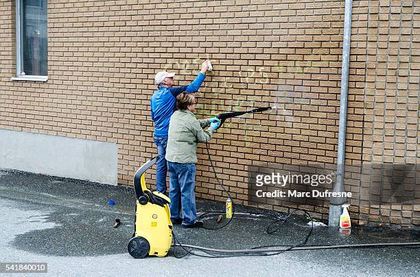 man and woman cleaning graffiti on their brick wall - cleaning graffiti stock pictures, royalty-free photos & images