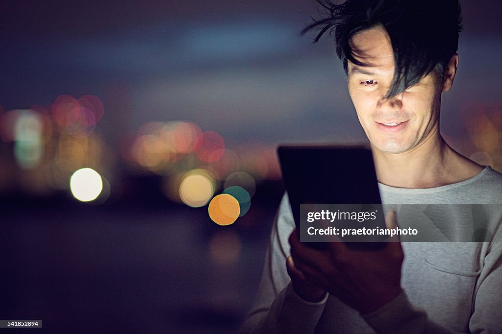 Jamanese man with tablet in the the night