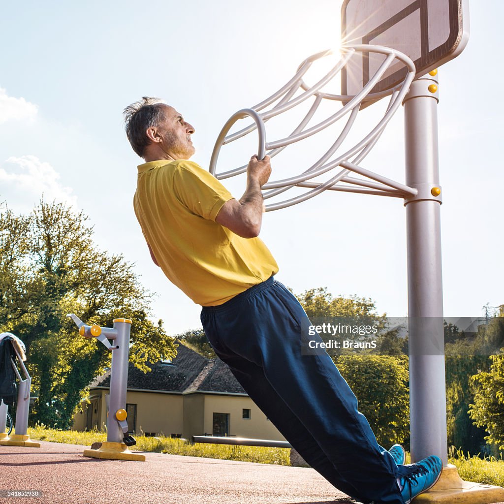 Senior man doing strength exercises at the outdoor gym.