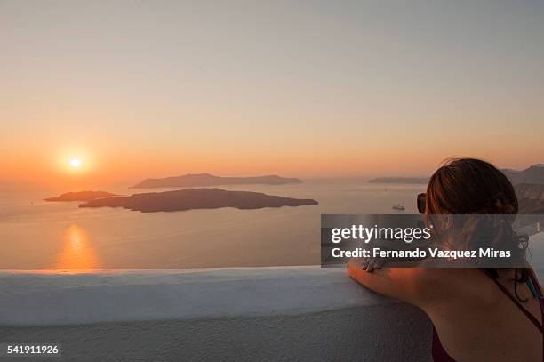 woman observing an amazing sunset in santorini island, cyclades islands, greece - fira santorini stock pictures, royalty-free photos & images