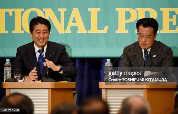 Japanese Prime Minister and ruling Liberal Democratic Party leader Shinzo Abe smiles while talking to Democratic Party leader Katsuya Okada during a...