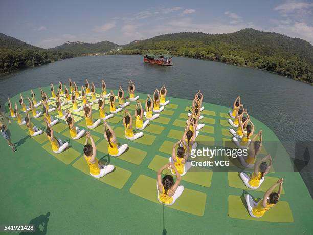 Yoga enthusiasts practice yoga on the water of Shiyan Lake on June 21, 2016 in Changsha, Hunan Province of China. About 100 yoga enthusiasts perform...