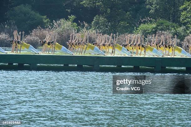 Yoga enthusiasts practice yoga on the water of Shiyan Lake on June 21, 2016 in Changsha, Hunan Province of China. About 100 yoga enthusiasts perform...