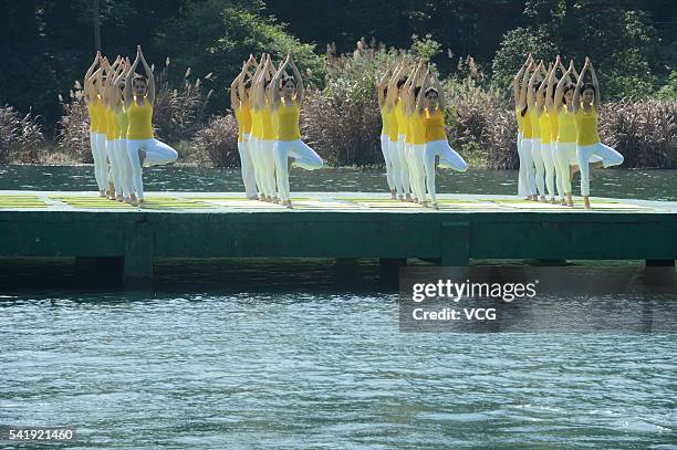 Yoga enthusiasts practice yoga on the water of Shiyan Lake on June 21, 2016 in Changsha, Hunan Province of China. About 100 yoga enthusiasts perform...