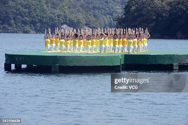 Yoga enthusiasts practice yoga above water of Shiyan Lake on June 21, 2016 in Changsha, Hunan Province of China. About 100 people performed yoga to...