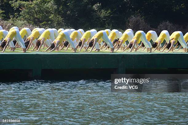 Yoga enthusiasts practice yoga above water of Shiyan Lake on June 21, 2016 in Changsha, Hunan Province of China. About 100 people performed yoga to...