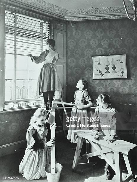 Housewifery lesson, Dulwich Hamlet School, Dulwich Village, London, 1908. Four schoolgirls are busy taking the slats out of venetian blinds and...