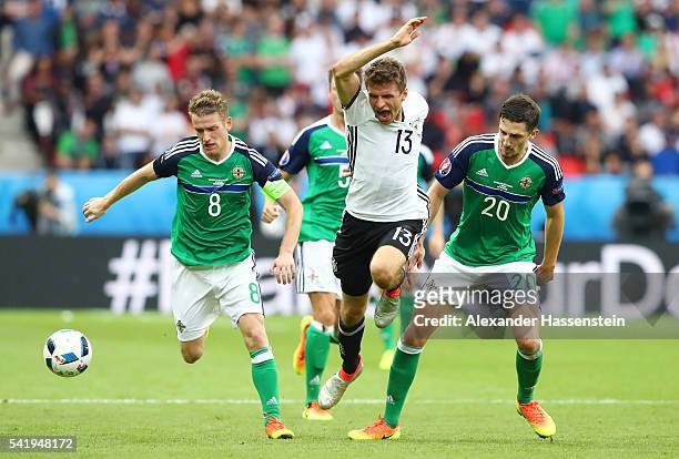 Thomas Mueller of Germany is challenegd by Steven Davis and Craig Cathcart of Northern Ireland during the UEFA EURO 2016 Group C match between...
