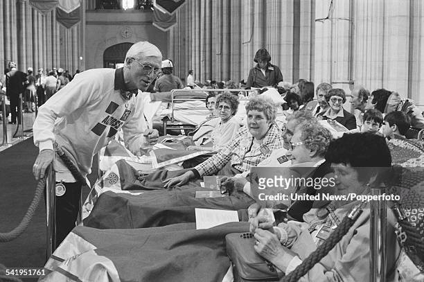 English DJ and television presenter Jimmy Savile talks with hospital patients prior to a visit by Pope John Paul II to St George's Cathedral,...