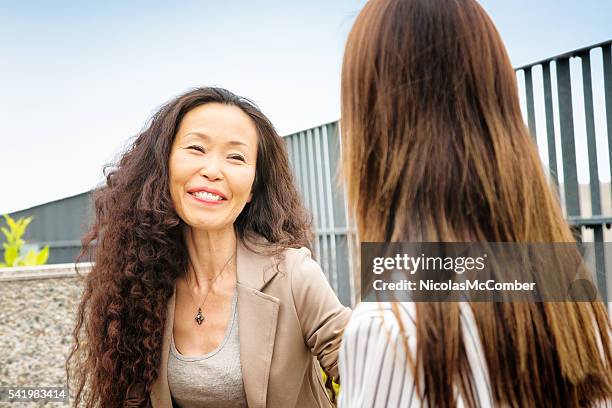 feliz mulher madura japonês mentor sorri para seu protegee - frizzy - fotografias e filmes do acervo