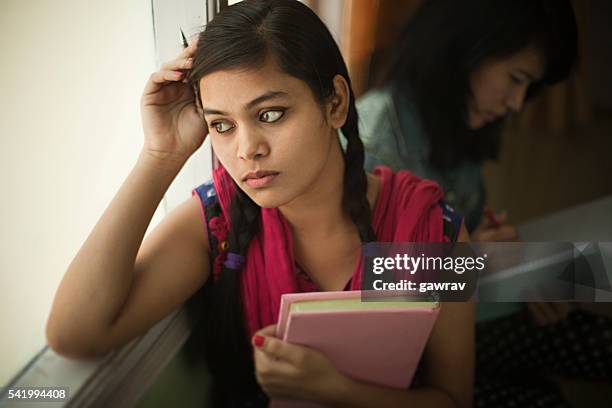 indoor, serene asian teenage girl student near window with book. - indian college girls stock pictures, royalty-free photos & images