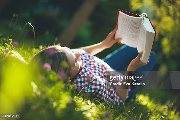 young woman reading in the garden - read book outside young woman bildbanksfoton och bilder