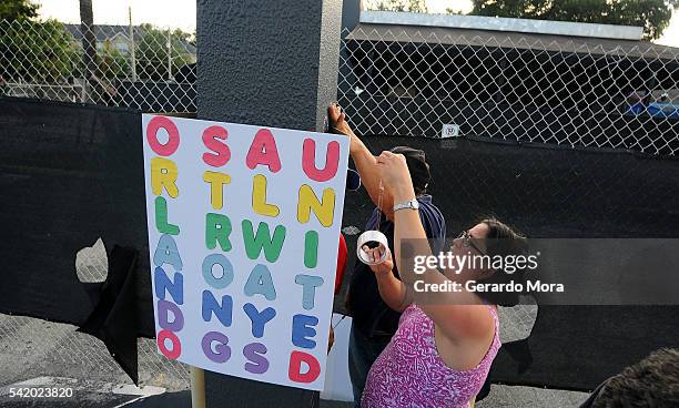 People leave signs and flowers for the victims of the Pulse Nightclub shooting at the front of the nightclub building on June 21, 2016 in Orlando,...