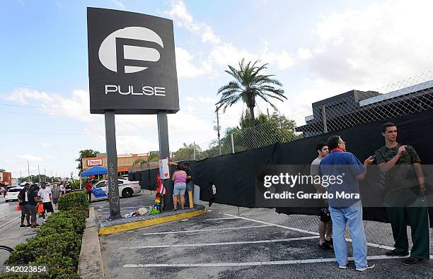 People leave signs and flowers for the victims of the Pulse Nightclub shooting at the front of the nightclub building on June 21, 2016 in Orlando,...