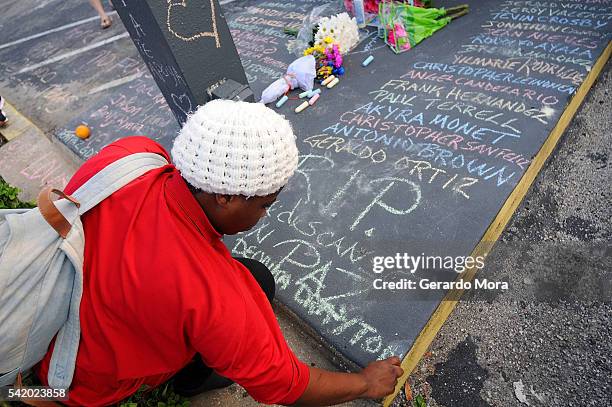 Destiny Jackson writes a message for the victims of the Pulse Nightclub shooting at the front of the nightclub on June 21, 2016 in Orlando, Florida....
