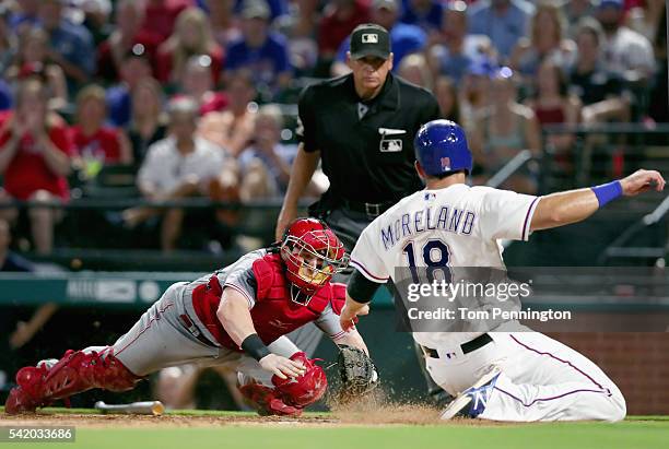 Tucker Barnhart of the Cincinnati Reds tags out Mitch Moreland of the Texas Rangers at home plate in the bottom of the eighth inning at Globe Life...