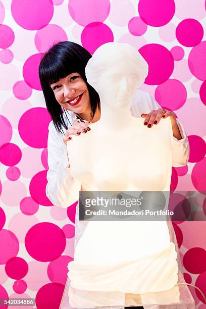 Italian beautician and blogger Cristina Fogazzi smiling and leaning against a lamp shaped as a Greek bust. Her nickname on the web is Estetista...