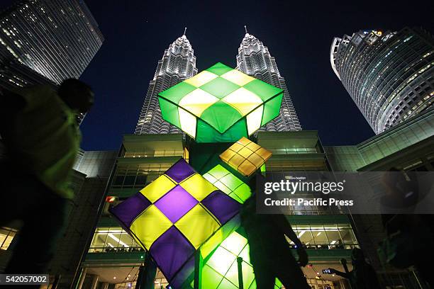 People walk past a huge Ketupat Raya decorations ahead of Hari Raya Aildilfitri celebrations at a shopping mall in front of Petronas Twin Towers in...