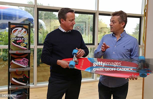 British Prime Minister David Cameron listens as he talks with Managing Director of Shiner Ltd. Charlie Allen, at the sports equipment distributor's...