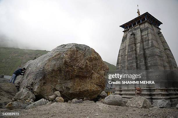In this photograph taken on June 20 an Indian Hindu devotee pays his respects at the rock which partially diverted floodwaters around the Kedarnath...