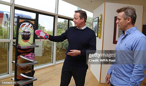 British Prime Minister David Cameron talks with Managing Director of Shiner Ltd. Charlie Allen, at the sports equipment distributor's offices on June...