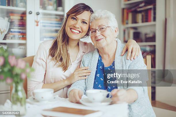 social worker is visiting a senior woman - young woman with grandmother stockfoto's en -beelden
