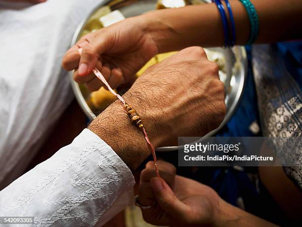 tying a rakhi on a wrist - akhi stock pictures, royalty-free photos & images