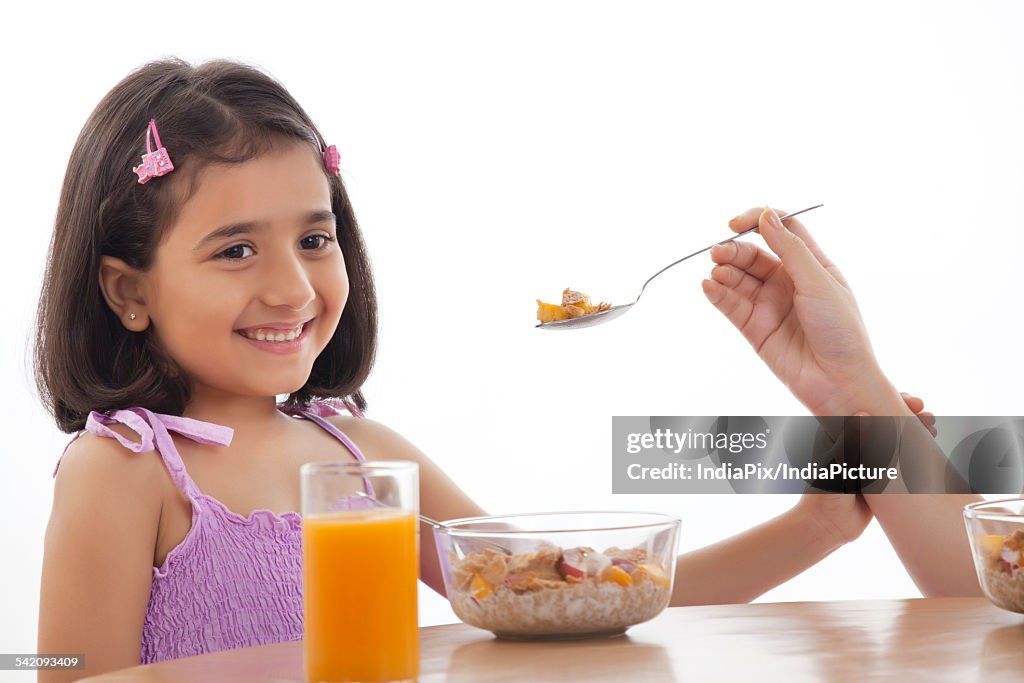 Mother feeding her daughter breakfast