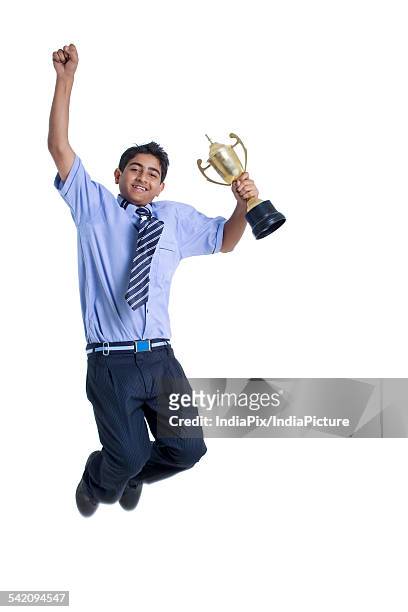 smiling young boy jumping in air with trophy against white background - life after stroke awards 2011 stock pictures, royalty-free photos & images