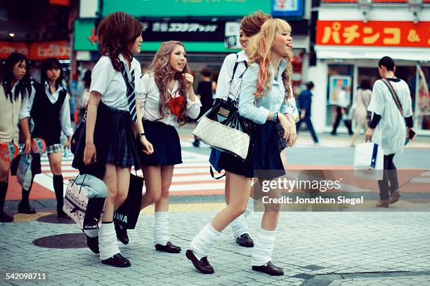 Japanese school girls with funky and crazy hair styles and mini skirts crossing the street in Shibuya, Tokyo.