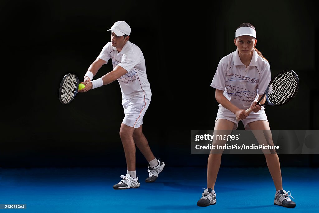 Man and woman playing tennis doubles at court