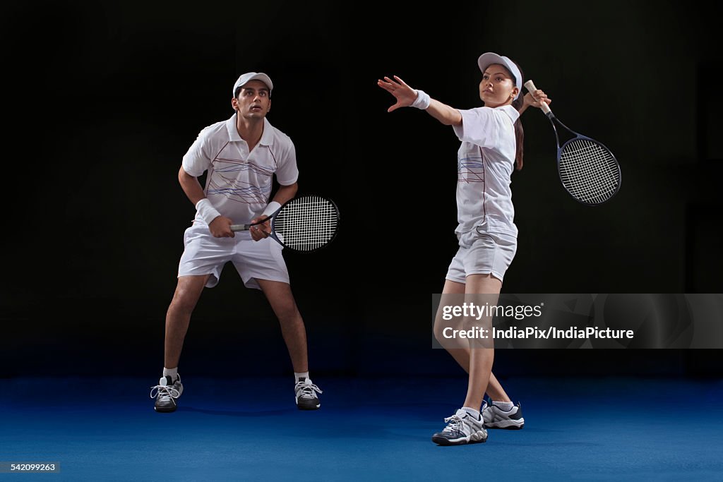 Male and female players playing tennis doubles at court