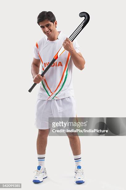 full length portrait of happy young man holding hockey stick isolated over gray background - hockey background stockfoto's en -beelden