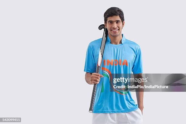 portrait of happy male hockey player with stick standing against white background - hockey background stockfoto's en -beelden