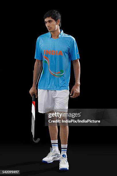 thoughtful young hockey player holding stick isolated over black background - hockey background stockfoto's en -beelden