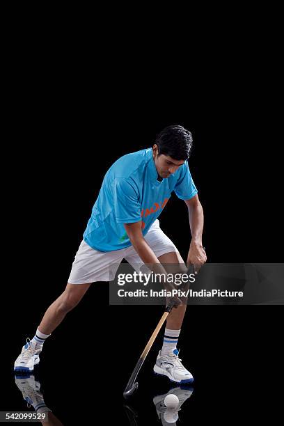 an indian man in sportswear practicing hockey isolated over black background - hockeyschläger stock-fotos und bilder