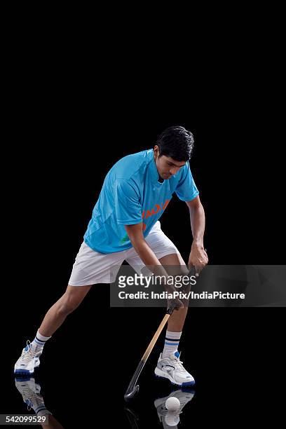an indian man in sportswear practicing hockey isolated over black background - hockey player black background stock pictures, royalty-free photos & images