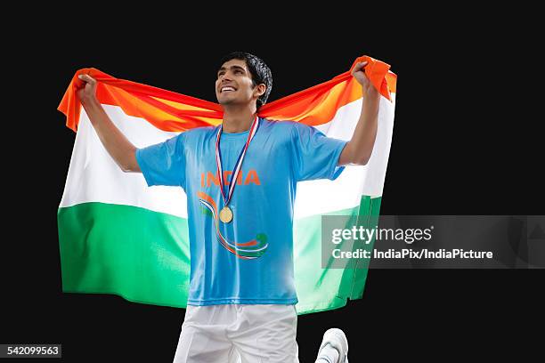 young hockey player looking up as he holds indian flag with pride against black background - hockey player black background stock pictures, royalty-free photos & images