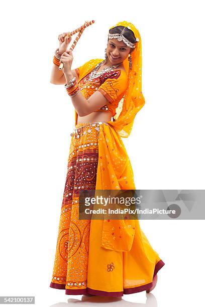 portrait of happy young woman in chaniya choli performing dandiya raas against white background - dandiya ストックフォトと画像