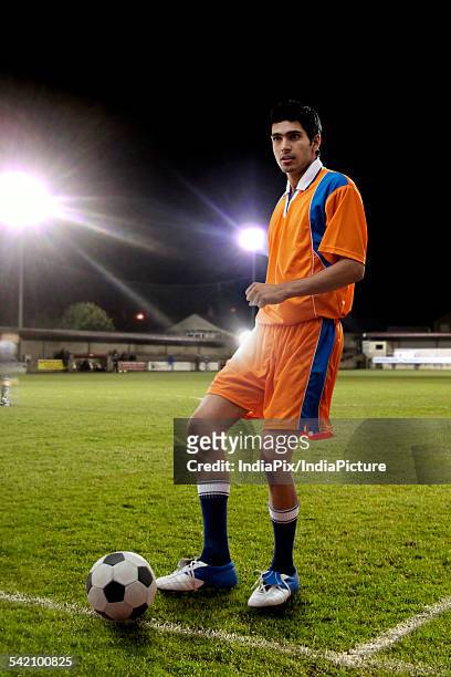 full length of young male player kicking soccer ball on field - indian football stock pictures, royalty-free photos & images