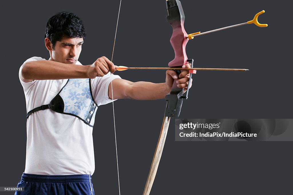 An Indian male archer aiming over black background